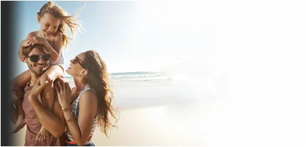 Happy couple on beach with child after successful fear of flying hypnotherapy treatment