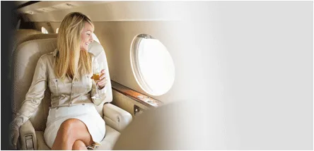 fear of flying hypnosis treatment - happy woman on private jet with champagne looking out of window