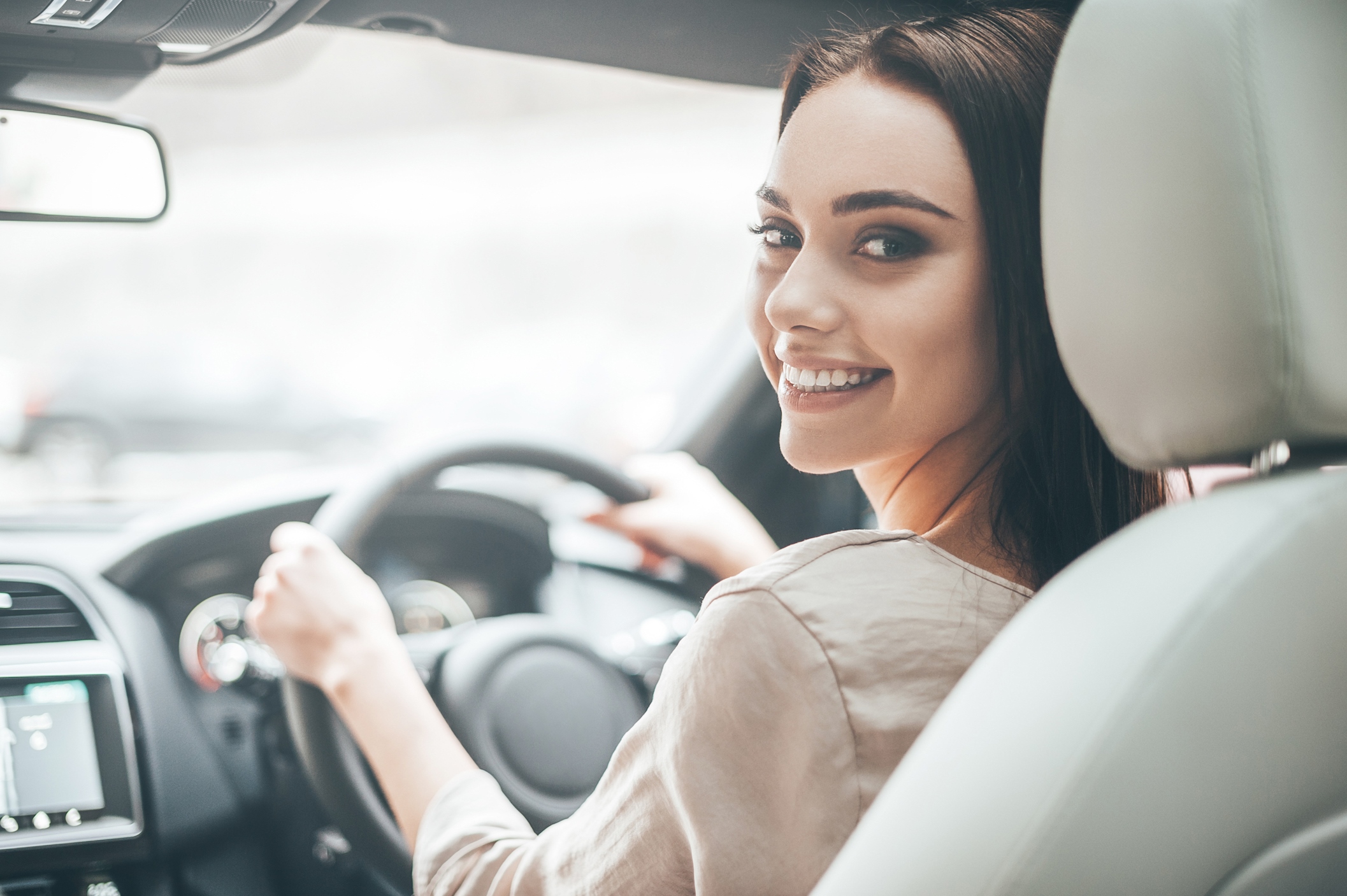 Smiling woman confidently driving a car, symbolizing success from fear of driving hypnotherapy.