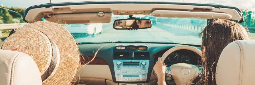 Two women enjoying freedom of the open road in a convertible after phobia hypnotherapy.